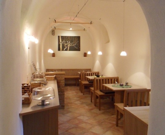 Ferienwohnung Kronsteiner, © Gästhaus Kranister Ein gemütlicher Frühstücksraum mit Holzmöbeln und gewölbter Decke.