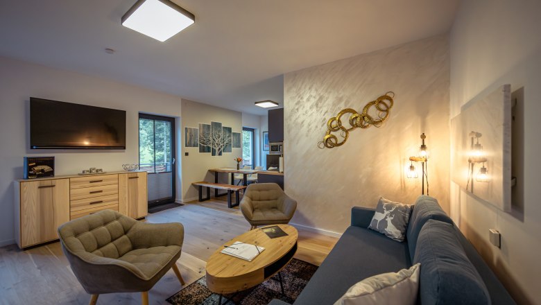Ötscher Lodge, © Niederösterreich Werbung / Maximilian Pawlikowsky Modern eingerichtetes Wohnzimmer mit Sofa, Sesseln, TV und Esstisch.