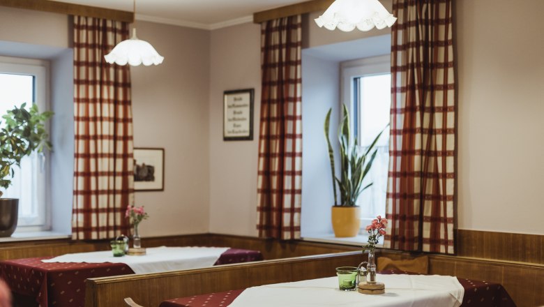 Einladende Wirtshausstube, © Niederösterreich Werbung/David Schreiber Gemütliche Wirtshausstube mit Holzmöbeln, karierten Vorhängen und dekorierten Tischen.