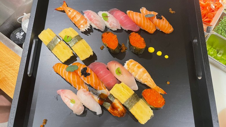 TD-Kekko-Sushi, © Alex Wu Ein schwarzes Tablett mit einer Auswahl an Sushi, darunter Nigiri und Maki, dekoriert mit Kaviar und Kräutern.