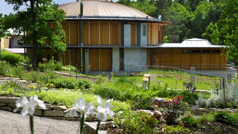 Amethyst Welt Maissau, © Natur im Garten/Alexander Haiden Rundes Gebäude mit Holzwänden und Garten im Vordergrund.