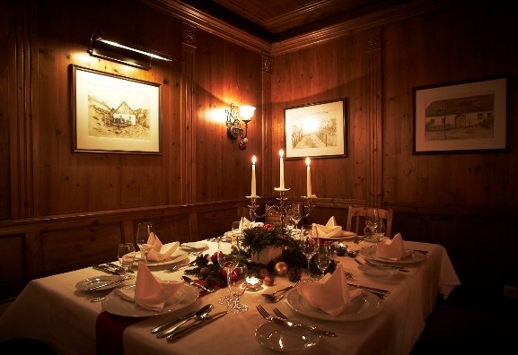 festlich gedeckte Weinstuben, © Steigenberger Hotel and Spa, Andreas Hofer Festlich gedeckter Tisch in einer gemütlichen Weinstube mit Kerzenlicht und Holzwänden.