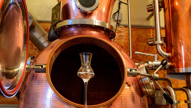 Brennerei mit Schnapsglas, © Wirtshausbrennerei Krenn Kupferne Destillationsanlage mit einem Schnapsglas im Vordergrund.