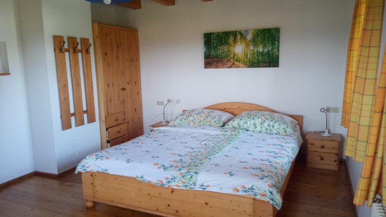 FW "Ziegelstadel", © Blumentalhof Schlafzimmer mit Holzbett, Nachttischen, Kleiderschrank und Wandbild eines Waldes.