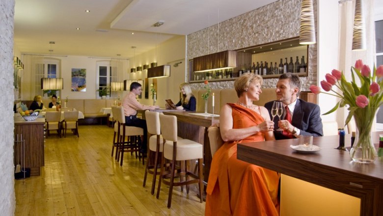 Restaurant - Die Residenz, © Die Residenz, Margit Zulehner Ein elegantes Restaurant mit Paaren an Tischen und einer Bar.