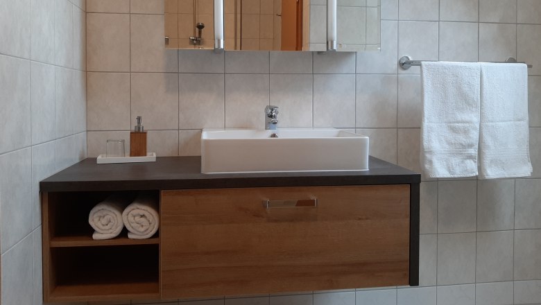 Bad, © Gerhard Auer Modernes Badezimmer mit Waschbecken, Handtüchern und Spiegel.