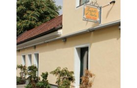 mit Schanigarten, © Herold Außenansicht eines gelben Gebäudes mit einem Schild "Fratelli d'Italia Caffè-Pizza" und Pflanzen vor der Fassade.