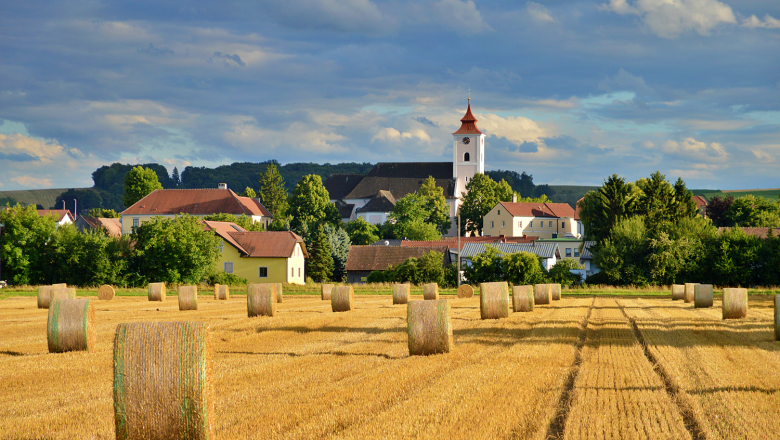 Gemeinde Michelhausen, © Marktgemeinde Michelhausen Landschaft mit Strohballen und Kirche in Michelhausen.