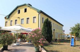 Gasthof Strasser, © Gasthof Strasser Gelbes Gebäude mit Terrasse und Spielplatz im Vordergrund.