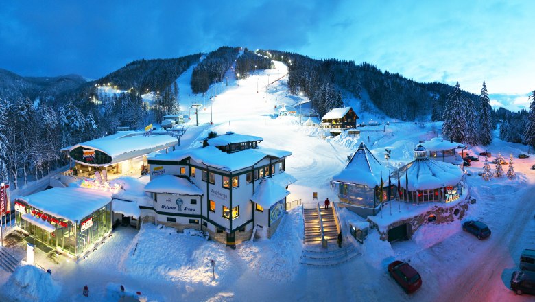 Zauberberg Talstation, © Franz Zwickl Winterliche Skistation bei Dämmerung mit beleuchteten Gebäuden und Pisten.