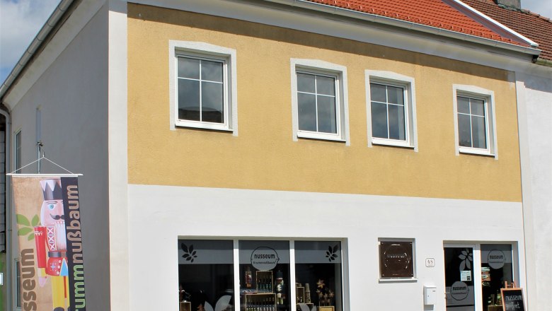 nusseum-krummnussbaum, © Johann Peham Außenansicht des Nusseums in Krummnussbaum mit gelber Fassade und Schaufenstern.