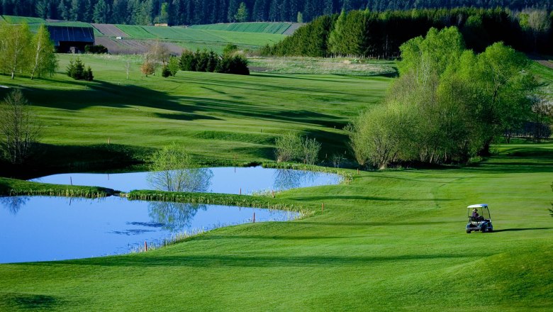 Golfclub Ottenstein, © Fotocredit: Helmut Lackinger, Diamond Club Ottenstein Golfplatz mit Teich und Golfwagen, umgeben von grünen Bäumen und Wiesen.