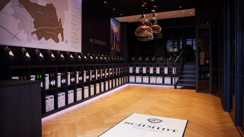 Selbstbedienungsshop, © Ben Leitern Innenansicht eines modernen Weinladens mit Holzfußboden, Weinflaschen in Regalen und einer großen Wandkarte.