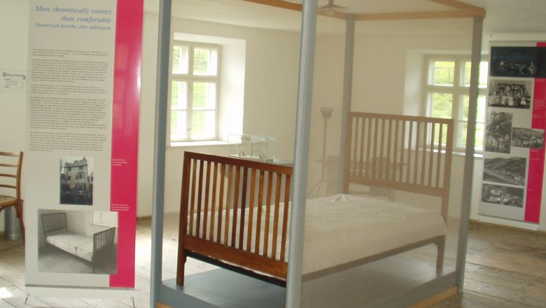 Wittgensteinausstellung, © Gemeinde Trattenbach Ausstellungsraum mit einem Bett hinter Glas und Informationstafeln.