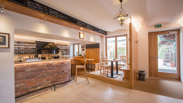 Weinbar Weinbau Klampfl, © hamp.at Innenansicht einer gemütlichen Weinbar mit Holzmöbeln und Ziegeltheke.