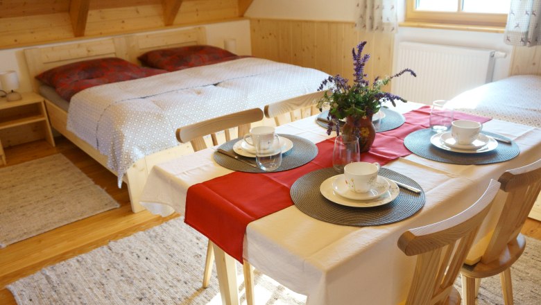Ferienwohnung, © Fam. Hotschek und Appel Gemütliches Zimmer mit Doppelbett und Esstisch, gedeckt für vier Personen.