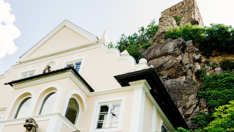 villa_schonthal-6_1, © Julius Hirtzberger Gelbe Villa neben Felsen mit Turm.