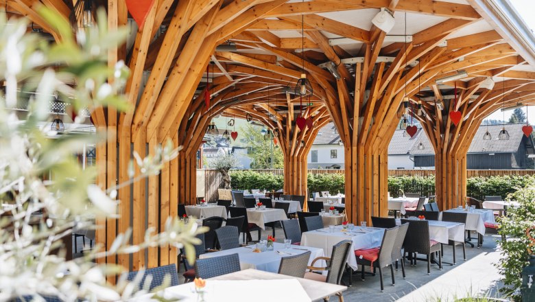 Moderner, schattiger Gastgarten, © Niederösterreich Werbung/David Schreiber Moderner Gastgarten mit Holzkonstruktion und gedeckten Tischen.