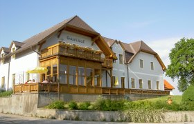 Gasthof Hagmann, © Gabriela Hagmann Ein traditioneller Gasthof mit Holzveranda und Blumen auf dem Balkon, umgeben von grüner Landschaft.