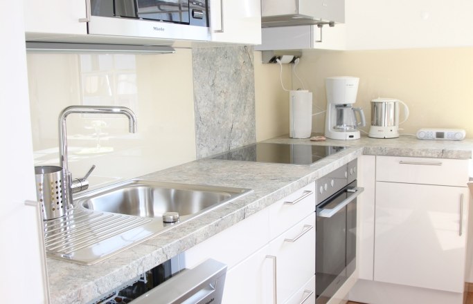 Altes Pförtnerhaus, © © Elisabeth Hofer Moderne Küche mit weißen Schränken, Spüle, Geschirrspüler, Mikrowelle und Kaffeemaschine.