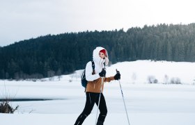 Langlaufen am Frauenwieserteich, © Waldviertel Tourismus, Line Sulzbacher Eine Person beim Skilanglauf auf einem verschneiten Feld vor einem Wald.