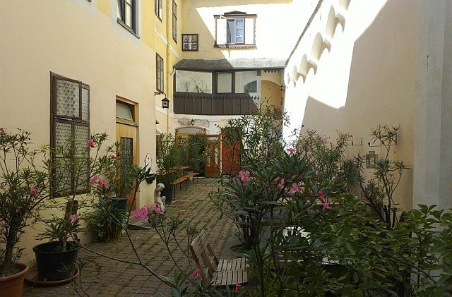 Hof im Sommer, © Norbert Stock Ein sonniger Innenhof mit Pflanzen und Sitzgelegenheiten.