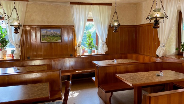 Gaststube Blunzenwirt, © Wiener Alpen Gemütliche Gaststube mit Holzmöbeln, weißen Vorhängen und Pflanzen auf der Fensterbank.