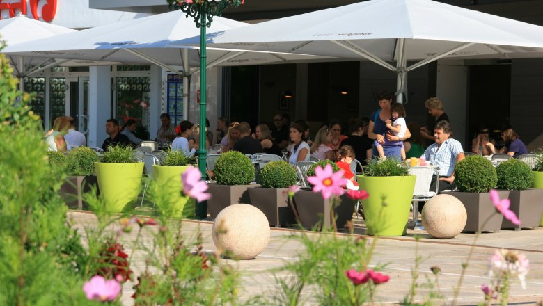 Cafe Konditorei Wagner Tulln, © Stadtgemeinde Tulln Außenbereich eines Cafés mit Menschen unter Sonnenschirmen.