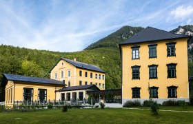 Thalhof Außenansicht, © Thalhof, Katrin Nusterer Außenansicht des gelben Thalhofs vor bewaldeten Bergen.