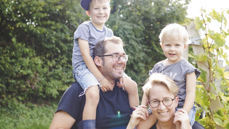 TDR-Familienfoto, © Buschenschank Buder Familie im Freien, zwei Erwachsene tragen Kinder auf den Schultern, sonniger Tag.