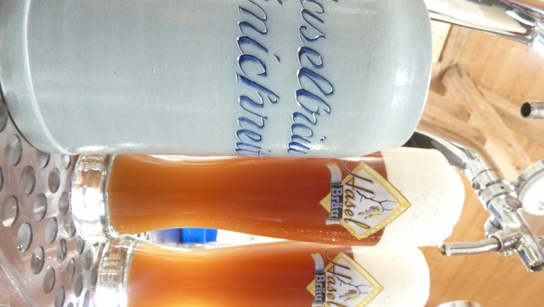 Wirtshausbrauerei Haselböck, © Wirtshausbrauerei Haselböck Zwei Gläser Bier und ein Krug mit der Aufschrift 'Haselbräu Münichreith' auf einem Tresen.