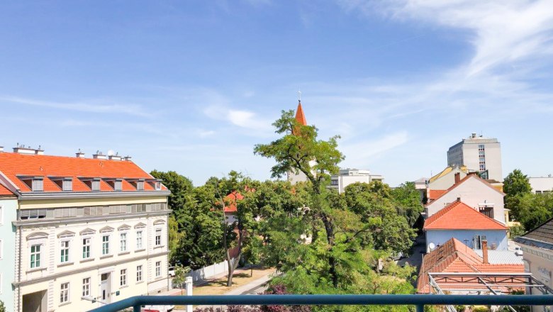 Aussicht ins Grüne, © Apartment am Stadtpark Städtische Aussicht mit Bäumen und Gebäuden unter blauem Himmel.