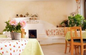 Frühstücksraum, © Familie Grün Gemütlicher Frühstücksraum mit Holzmöbeln, Pflanzen und einem kleinen Kamin.