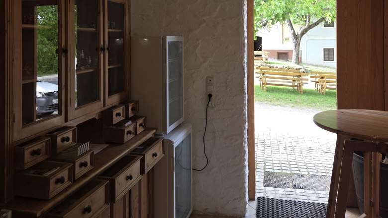 Radlerrast der Familie Krottendorfer, © Winzerhof Krottendorfer Innenraum mit Holzmöbeln und Blick nach draußen auf eine Terrasse mit Bänken.