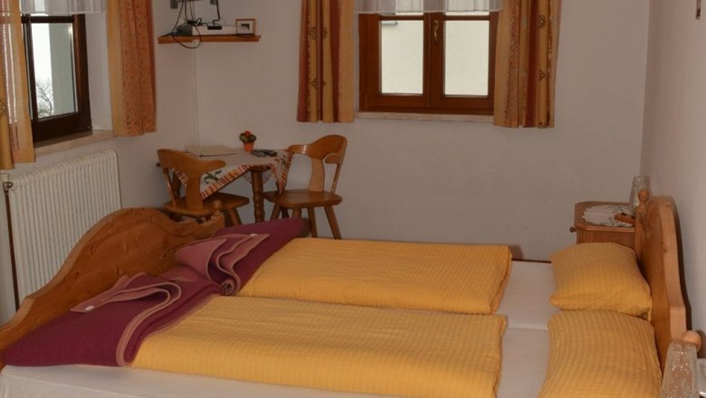Klein Schöntal, © Klein Schöntal Gemütliches Schlafzimmer mit Doppelbett, Holzmöbeln und kleinem Tisch mit Stühlen.