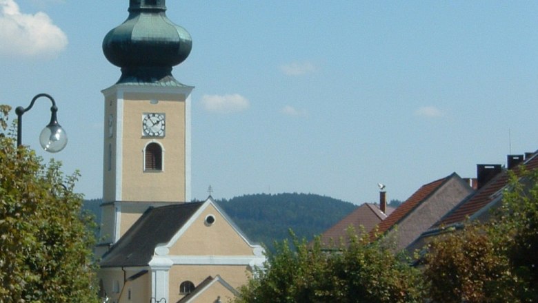 Gemeinde Thaya, © Gemeinde Thaya Kirche mit Zwiebelturm in einer kleinen Stadt, umgeben von Bäumen und Häusern.