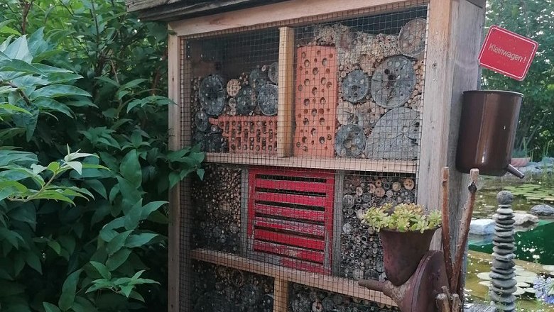 Nützlingshotel als Sichtschutz, © Tina Perina Ein Insektenhotel aus Holz mit verschiedenen Materialien gefüllt, steht in einem Garten neben Pflanzen.