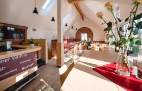 Heuriger Kropf, © Alexander Pfeffel Innenansicht eines modernen Heurigen mit Holzmöbeln und großen Fenstern.