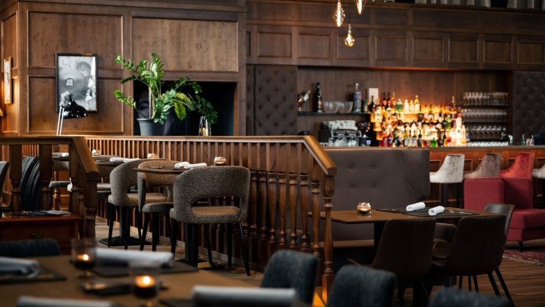 Zündwerk Living Room, © DERENKO DESIGN Elegantes Restaurant mit Holzmöbeln, Bar und gedämpfter Beleuchtung.