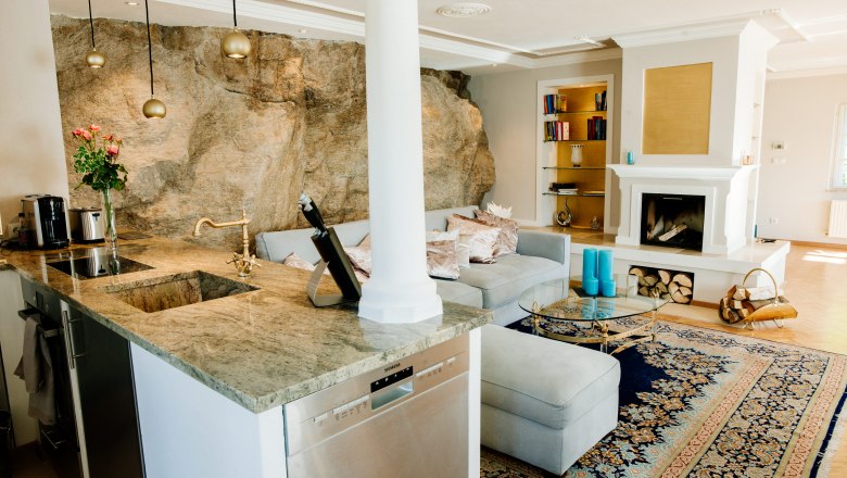 villa_schonthal-26_2, © Julius Hirtzberger Elegantes Wohnzimmer mit Kamin, Teppich und offener Küche.