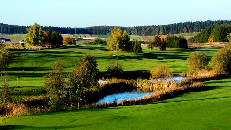 Restaurant Hettegger, © MG Rfd Grüne Golfplatzlandschaft mit Teich und Bäumen im Herbst.
