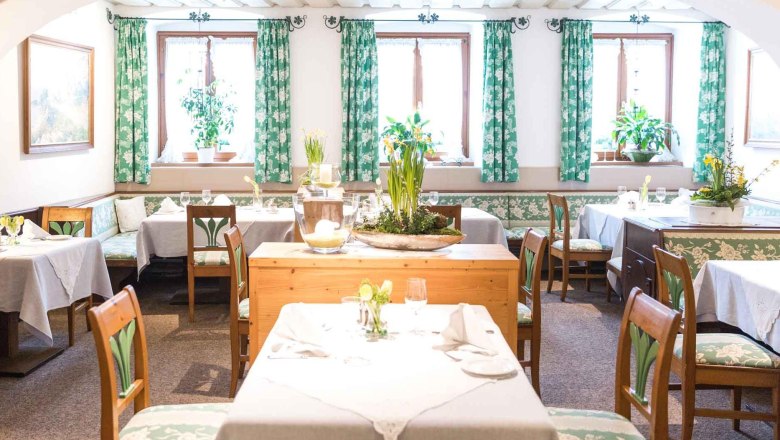 Innenräume im Loibnerhof, © Loibnerhof Gemütlicher Gastraum mit Holzmöbeln und grünen Vorhängen.