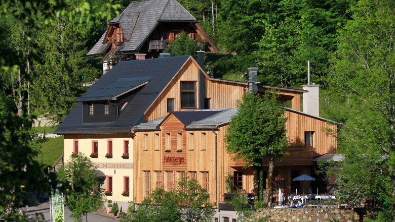Fahrnberger, © Dagmar Nahringbauer Ein traditionelles Gebäude mit Holzfassade in einer grünen Waldlandschaft.