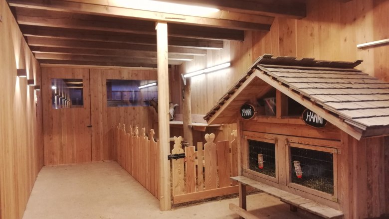 Ziegenstall, © Familie Rosinger Innenansicht eines Ziegenstalls aus Holz mit Ziegengehege und kleinem Häuschen.