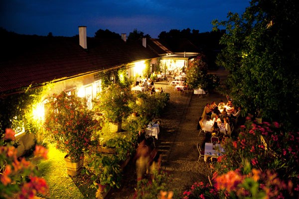 Gut Oberstockstall, © Robert Herbst Abendliche Gartenterrasse mit beleuchteten Tischen und Pflanzen.