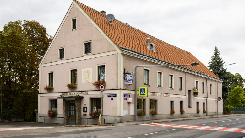 Wirtshaus in Pottenbrunn, © Niederösterreich Werbung/David Schreiber Ein traditionelles Wirtshaus mit rosa Fassade und roten Dachziegeln an einer Straßenecke in Pottenbrunn.