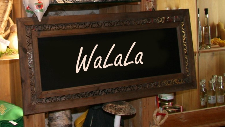 WaLaLa, © Kerstin Gall Ein dekoratives Holzschild mit der Aufschrift 'WaLaLa' in einem rustikalen Laden mit Regalen voller Produkte.