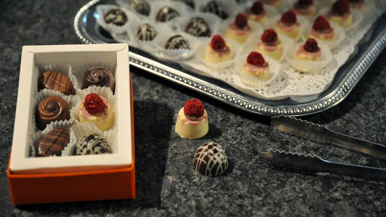 STYX Pralinen, © Styx Naturkosmetic GmbH Eine Schachtel Pralinen und ein Tablett mit Pralinen auf einem Tisch.