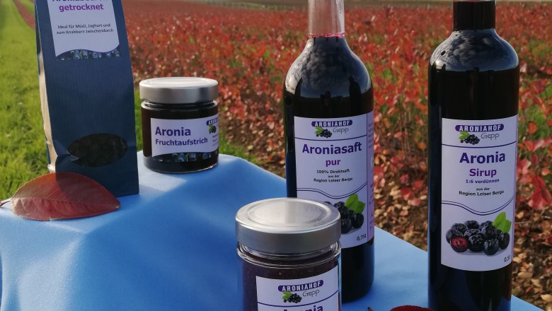 Aroniaprodukte, © Matthias Gepp Produkte des Aroniahofs Gepp auf einem Tisch vor einem Feld.