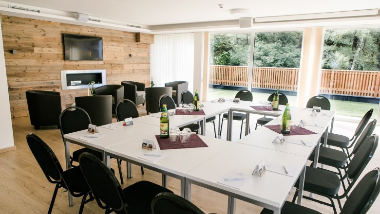 R&R Residenzen Hotel, © Doris Schwarz-König Konferenzraum mit U-förmiger Tischanordnung, Stühlen, Holzwand, Fernseher und großen Fenstern mit Blick ins Grüne.